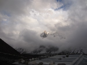 Mountains come out of the sky above the roofs of Larke Phedi on a cold, cloudy afternoon